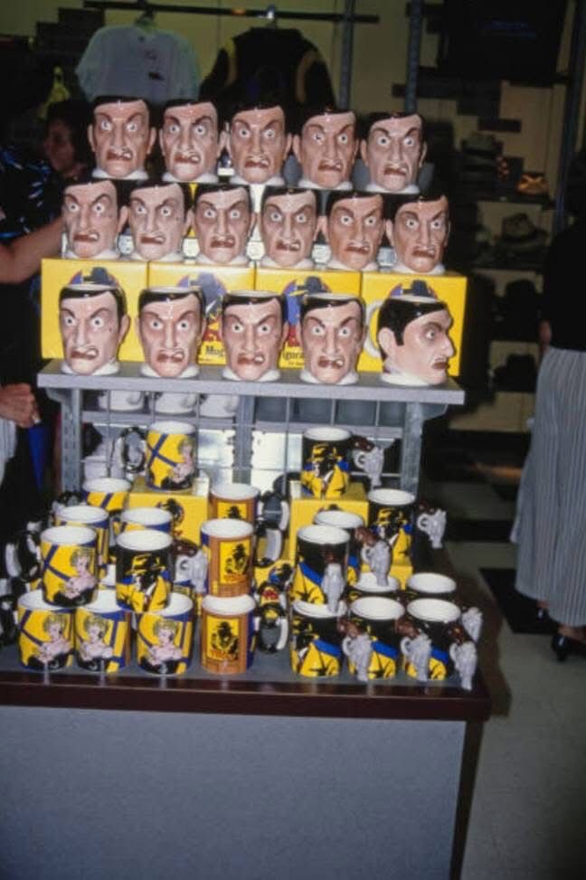 A collection of Dick Tracy mugs on display at a retail store, including a lot of terrifying Big Boy Caprice mugs shaped like Al Pacino’s head that everyone should get for filing taxes or for voting or whatever. They are great. Photo from the Dick Tracy Movie Fansite on the Facebook.