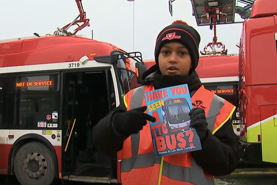 Screenshot of linked video showing young boy in front of TTC buses, pointing at his book titled "Have you seen a TTC bus?"