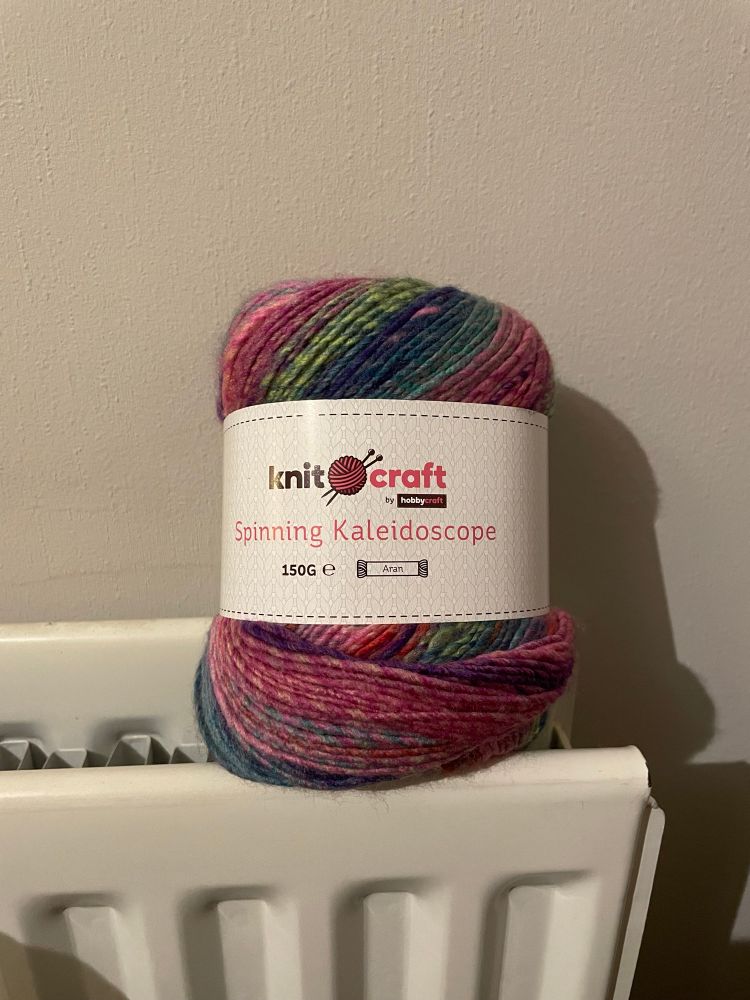 Photo of variegated yarn called “spinning kaleidoscope.” Is a mixture of pink, purple, green, blue and a little orange