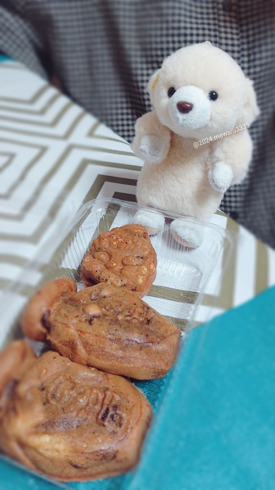 ツボの形のおまんじゅうの列を見るクマのぬいぐるみ