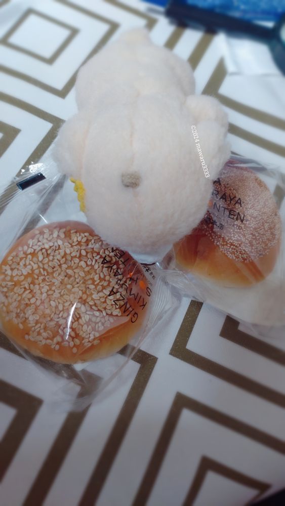 小さい木村家のあんぱん（袋入り）に覆いかぶさるクマのぬいぐるみ