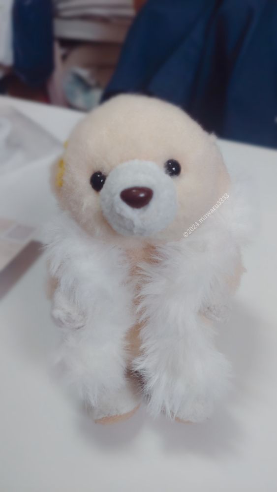 白いふわふわの毛を首に巻きつけるクマのぬいぐるみ