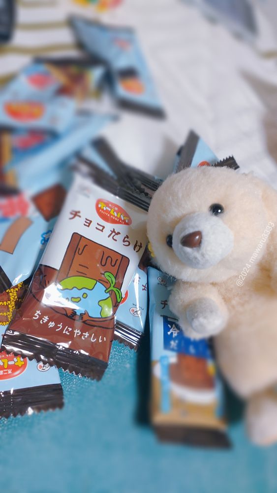 「ホームパイチョコだらけ」が広げてある机に寝そべるクマのぬいぐるみ