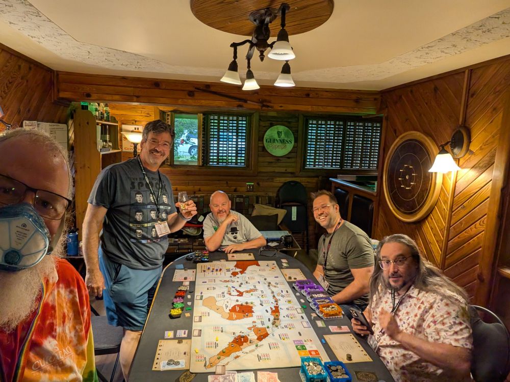 5 people sitting around a board game table on a basement 