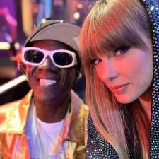 Flavor Flav cheesin in a photo with Taylor Swift