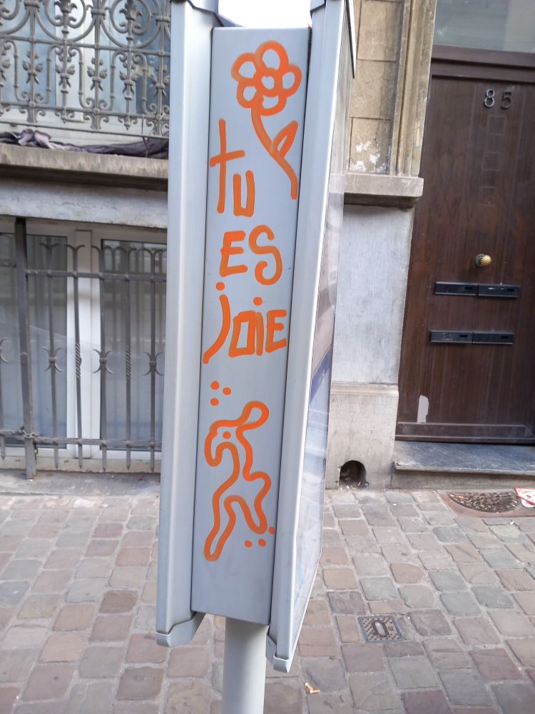 Dessin sur un panneau d'arrêt de bus, avec la mention "tu es joie"