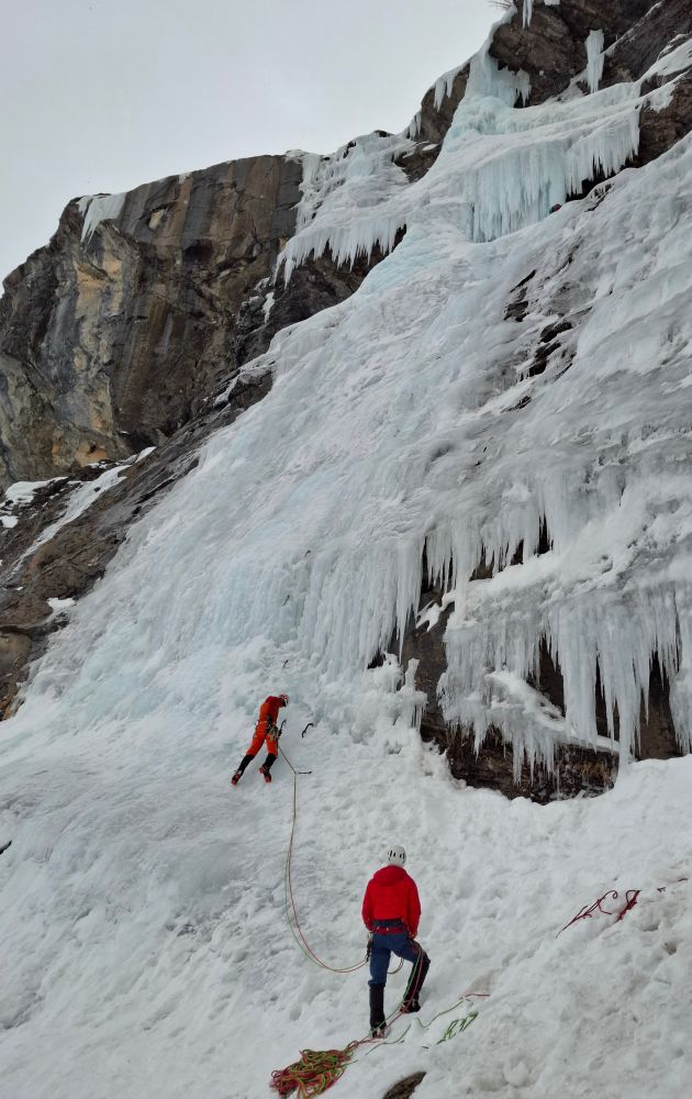 An ice climber and his belayer. The ice climber is attempting to climb a water fall 