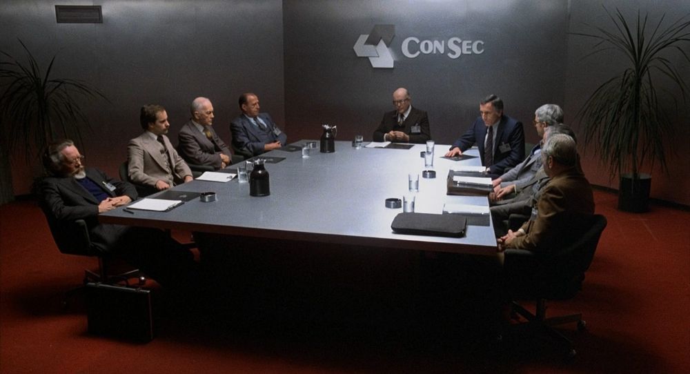A shot from Scanners. 8 senior executives, all middle-aged men, sit around a large metallic desk in the boardroom of the ConSec Corporation. The Chairman smokes a pipe. I have seen a glimpse of my future and I embrace it's grey splendour 