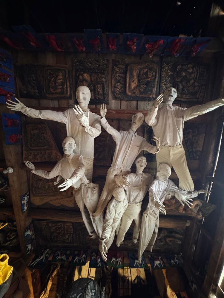 Photo of large human puppets with outstretched arms hanging from the painting and relief covered ceiling 