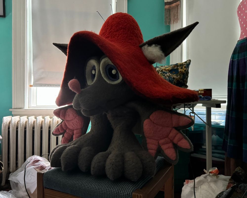 Photo of my needle felted fursuit partial of Fungus arranged like a small standing body on a chair.