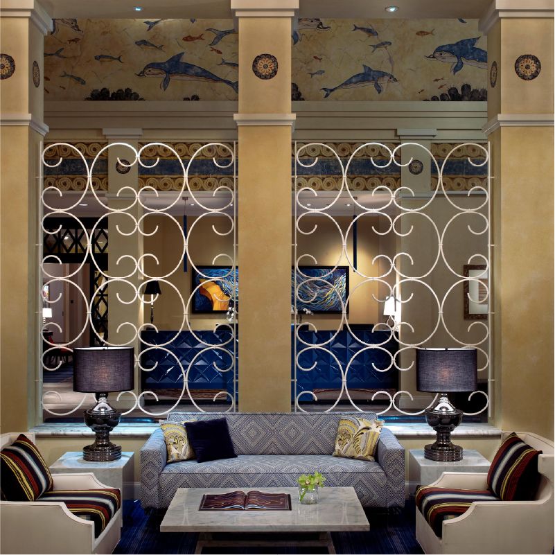 Photo of a hotel lobby with a gray couch and ornate metalwork behind it. 