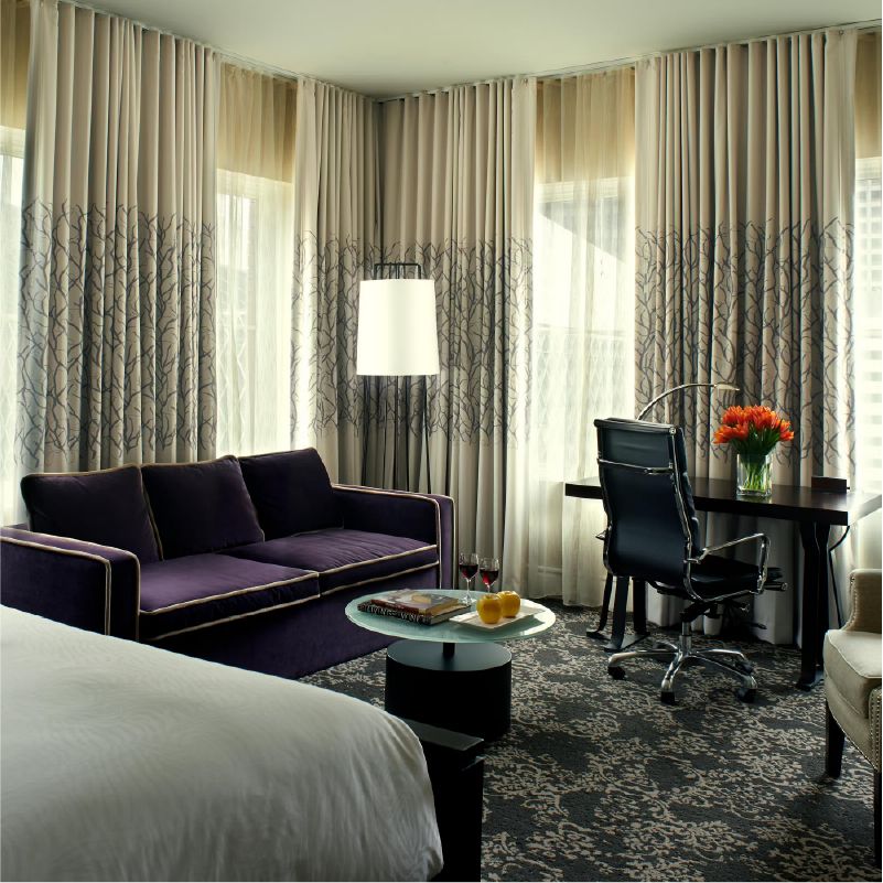 Photo of hotel room with a purple sofa and desk. 