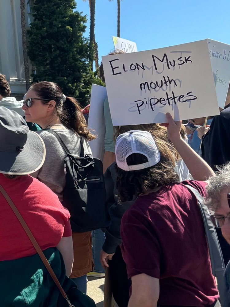 Protester holding sign "Elon musk mouth pipettes"