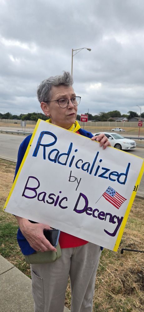 A protestor holds a sign reading " radicalized by basic decency "