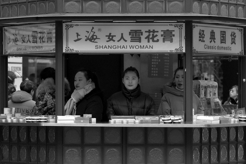 A black and white image of three Chinese women sitting on a booth labelled Shanghai Women. Taken in the Pudong area of Shanghai, 2019