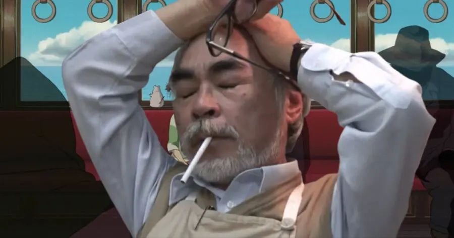 Hayoa Miyazaki, cigarette in mouth, leans back in his chair with his glasses pulled off in one hand and his other hand pressed against his head, a look of utter despair and defeat on his face. 