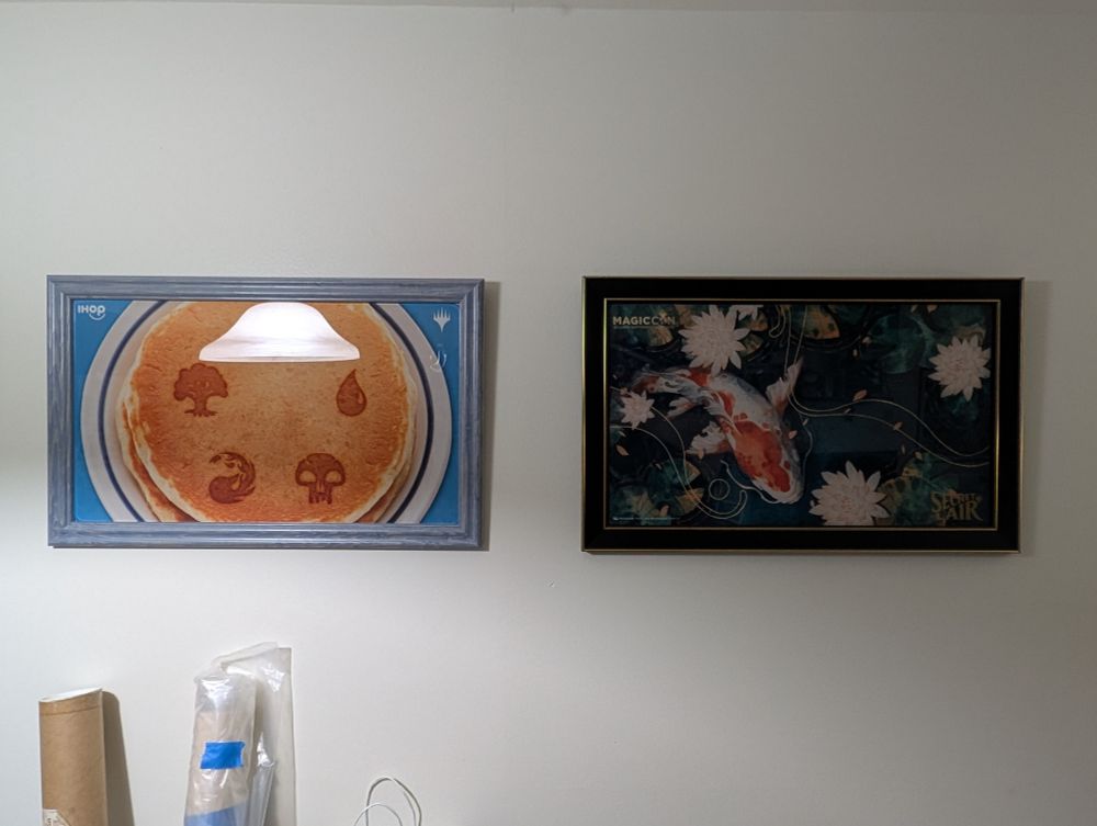 Dandan Secret Lair playmat framed and hanging next to the IHOP playmat