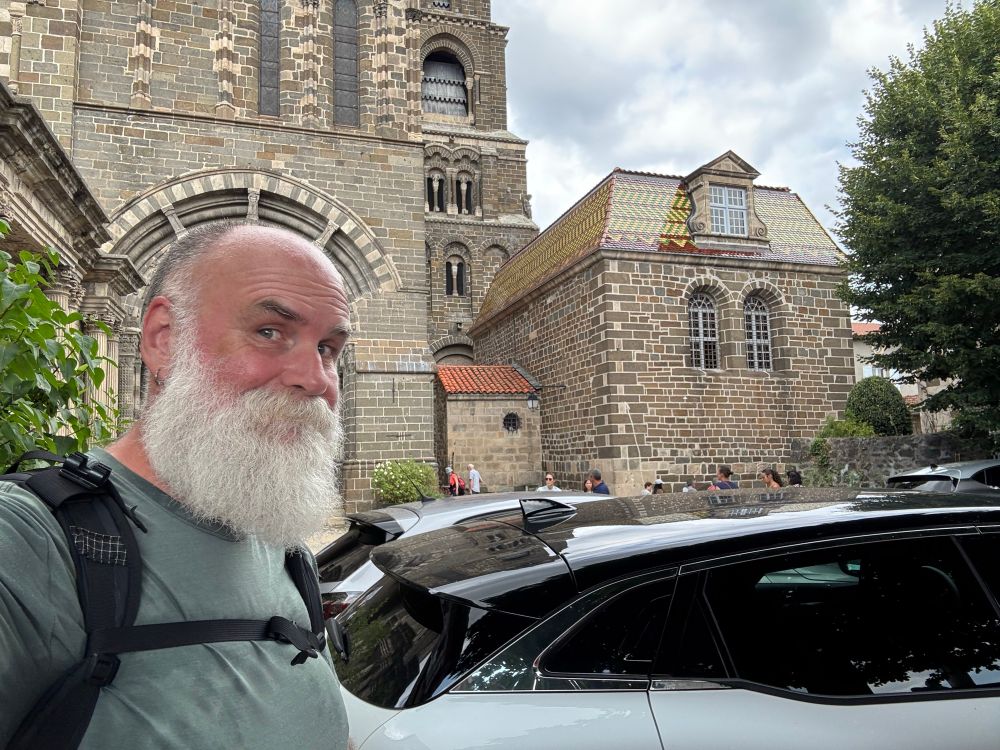 A white bearded dadbear standing in front of the cathedral at Le Puy-en-Velay, France