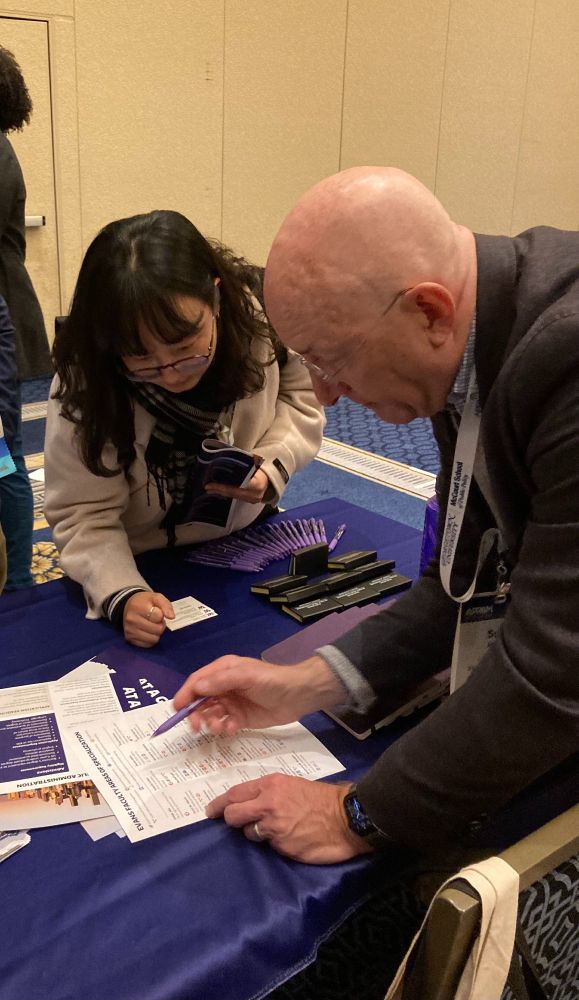 A faculty member and prospective student look at a list of Evans School faculty