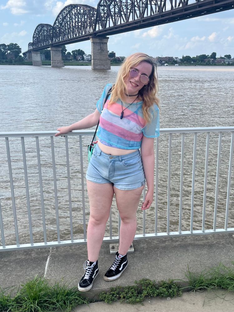 Me on the Ohio river waterfront being all cute in a trans flag mesh top and shorts