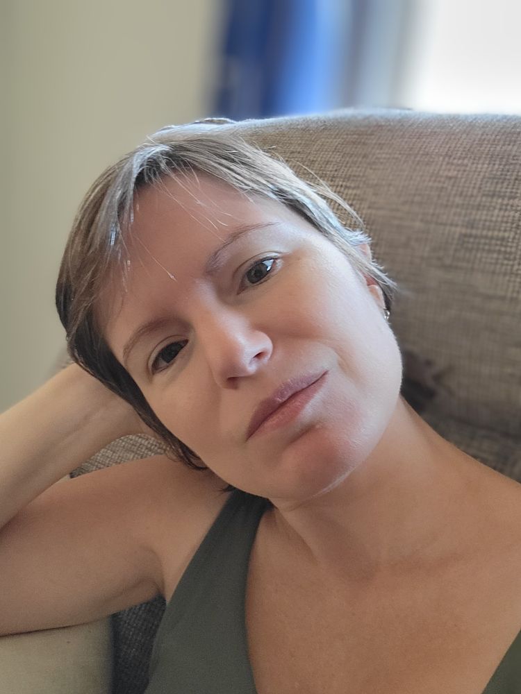 Photo of a pale white person with short hair wearing an olive green tank top