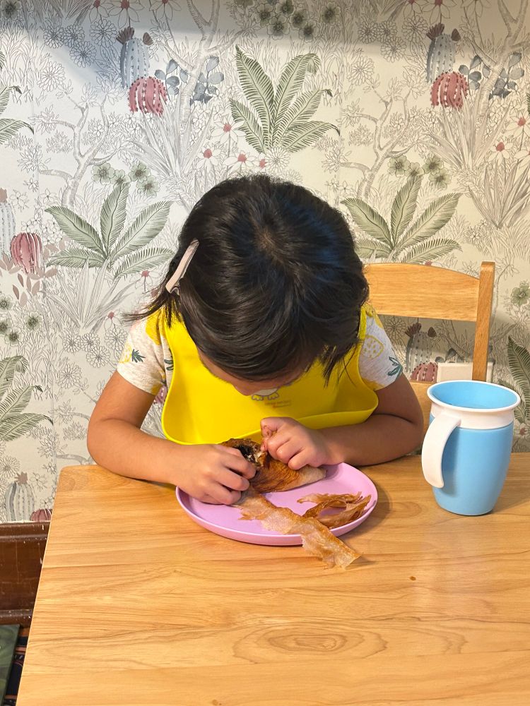 a child carefully pulls the chocolate from a pain au chocolat 