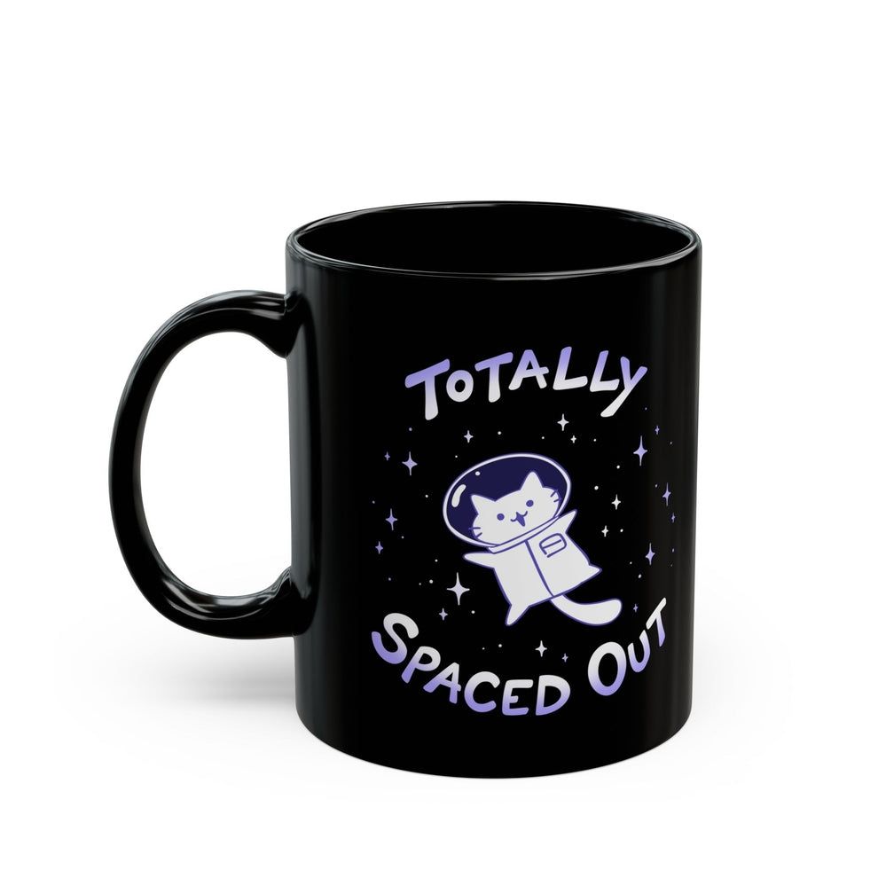 A black mug depicting a silly clueless looking white astronaut cat floating in space. The text above and below says "totally spaced out." 