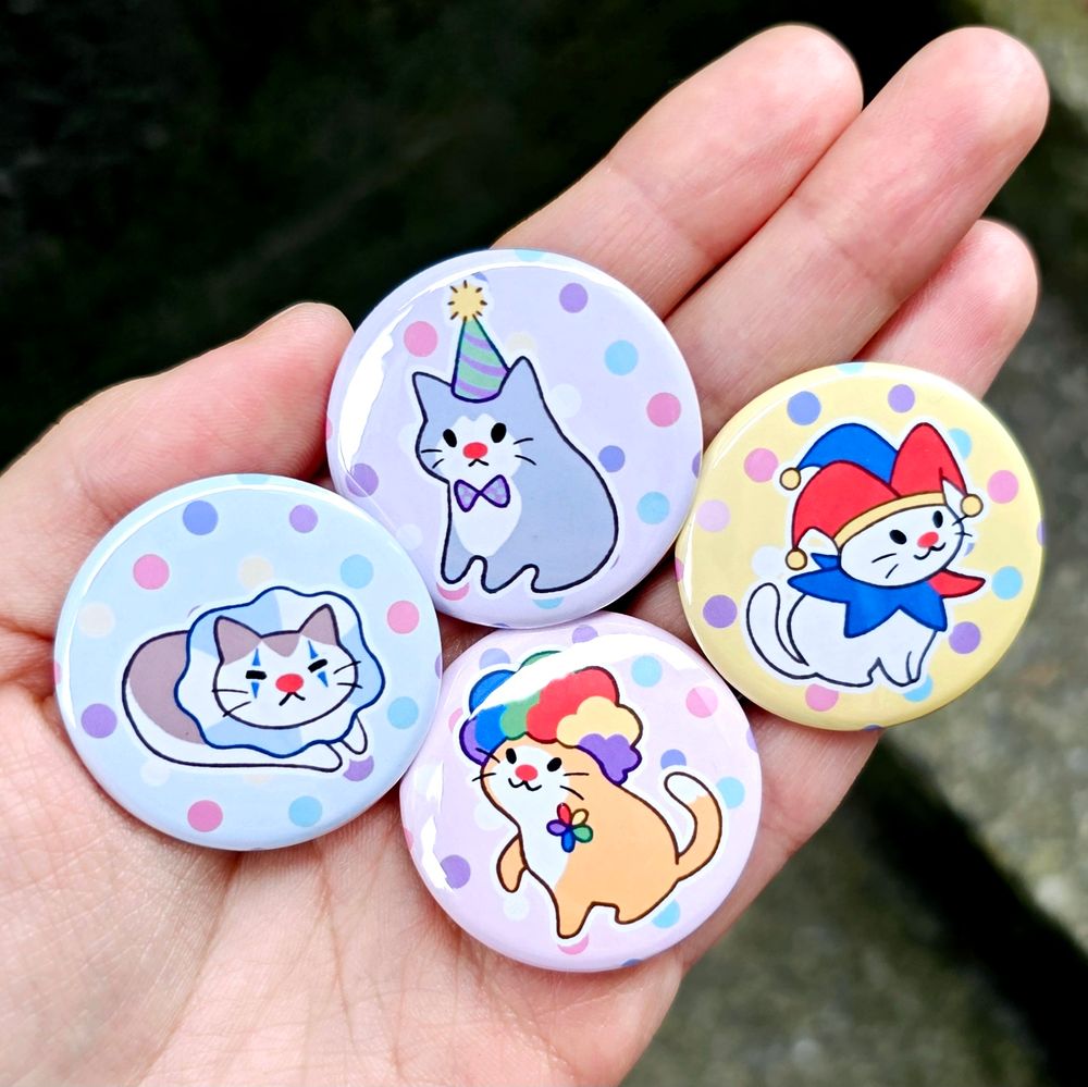 Four pinback buttons depicting various cute little cats dressed as clowns. 