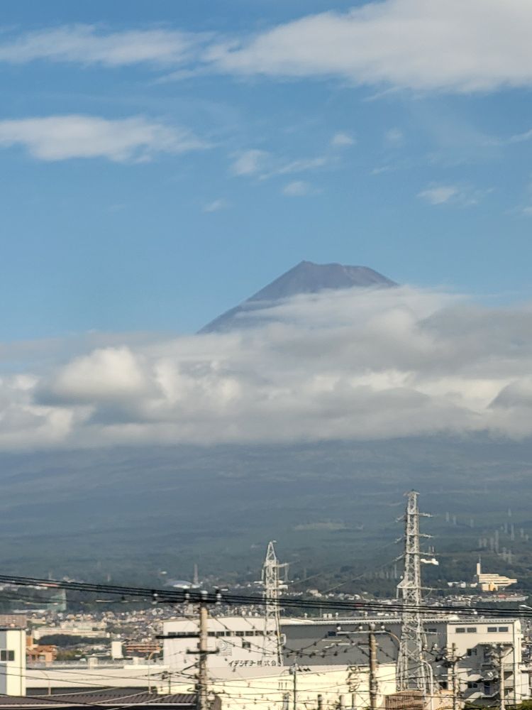 A photo of mount Fuji behind clouds taken from the shinkansen. The summit is visible above the clouds.
