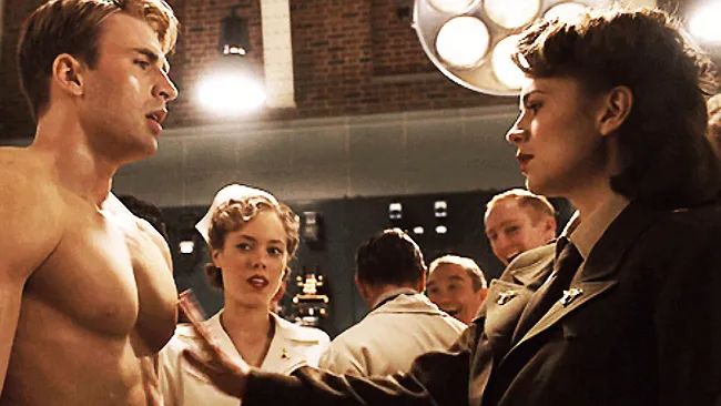 Peggy Carter reaching to Steve Rogers' pecs