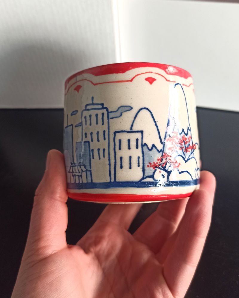 Close shot of the ceramic cup background between Fujisan and the hotsprings : a sall city and moutains
Blue underglaze lineart with watercolor effects, Red underglaze patterns and details (cherry blossom dots)
