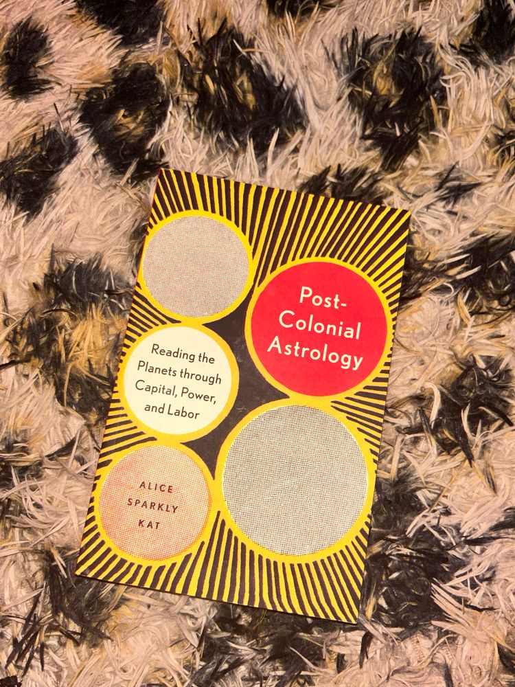 Post-Colonial Astrology book against leopard print rug backdrop 