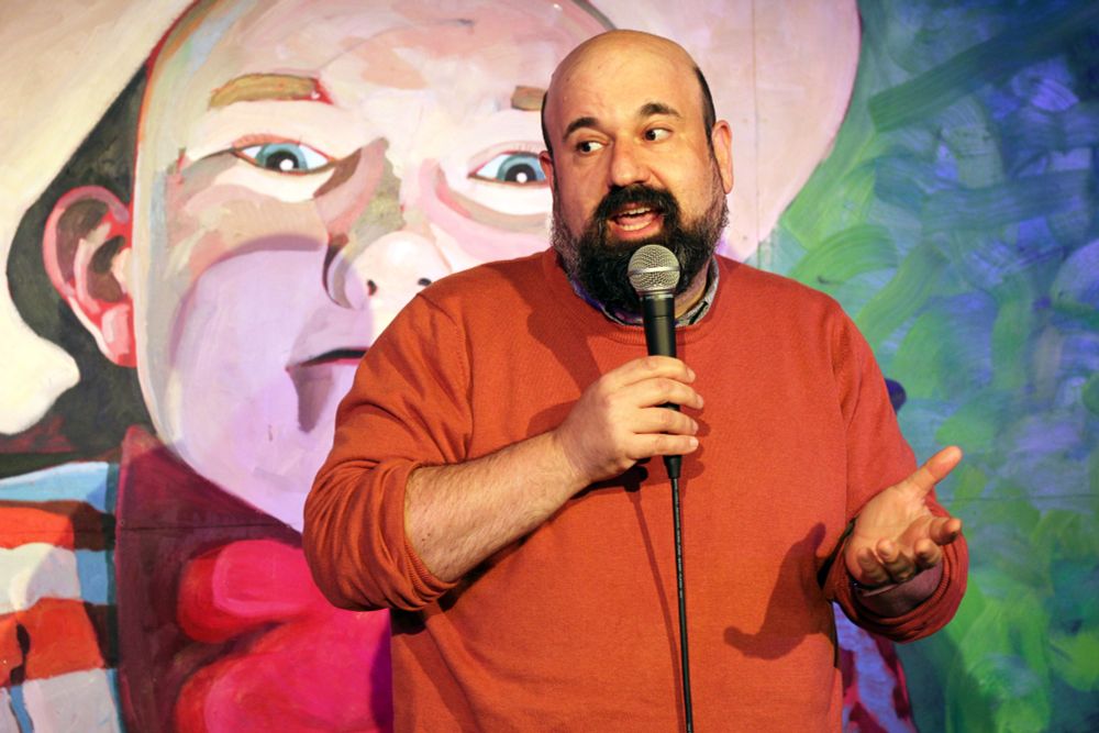Michael Frazer performing stand-up comedy at The Stand, Glasgow. There is a sign for Bright Club Glasgow.