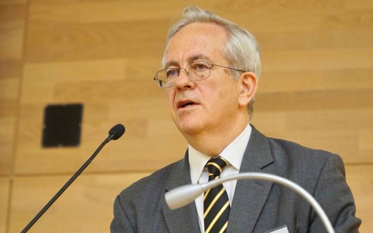The Rt Hon Sir Christopher Floyd, Former Lord Justice of Appeal and Honorary Professor at UCL Faculty of Laws, is standing in front of a microphone delivering a lecture.