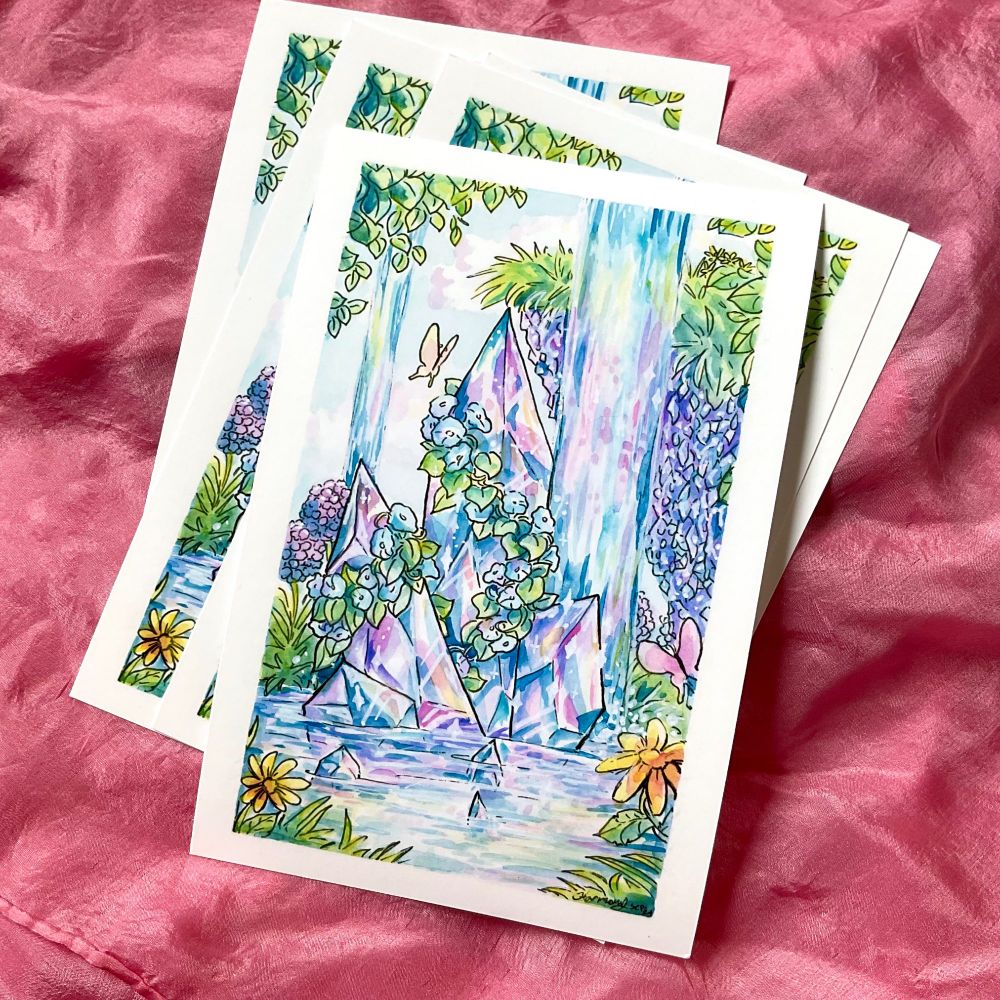 Photo is a small stack of art prints. The art is of crystals and water and flowers.