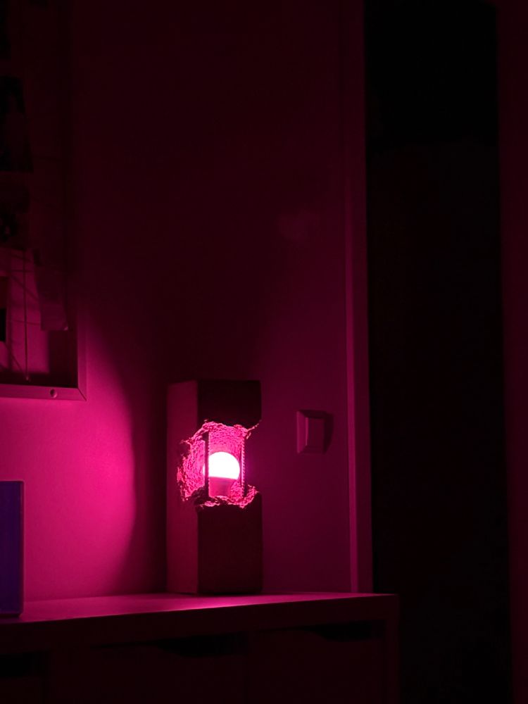 Betonlampe leuchtet in Pink in einem dunklen Raum