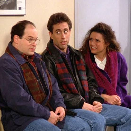 Elaine sitting with Jerry and George. She looks distressed and has just asked "How do we know that dog food's any good? Who tastes it?!" Jerry's eyebrows are raised and he's giving George side-eye and George is looking weirded out and a little curious and he's staring into space. 