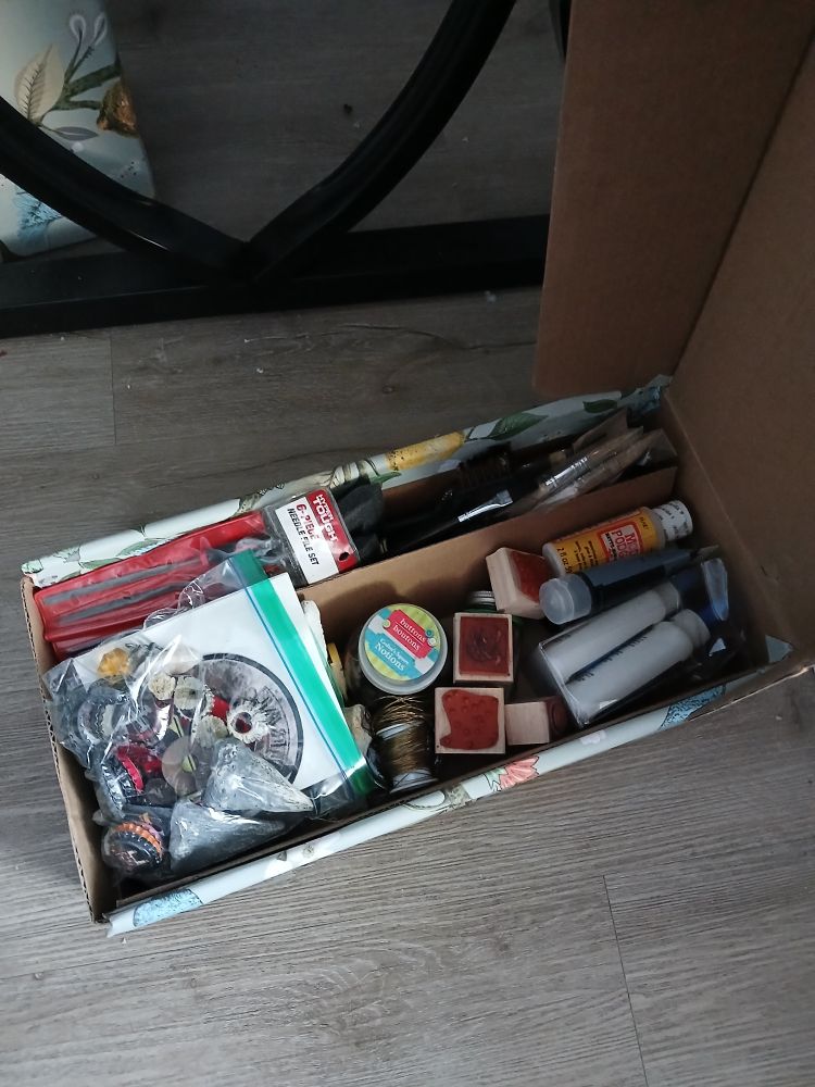 An open cardboard box full of craft shit
