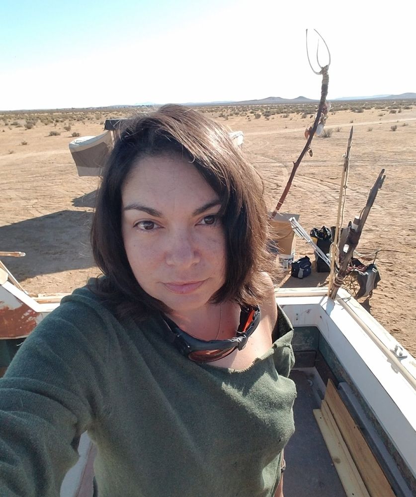 Karla in the middle of the desert, witn a perfectly non-criminal bone trident behind her.