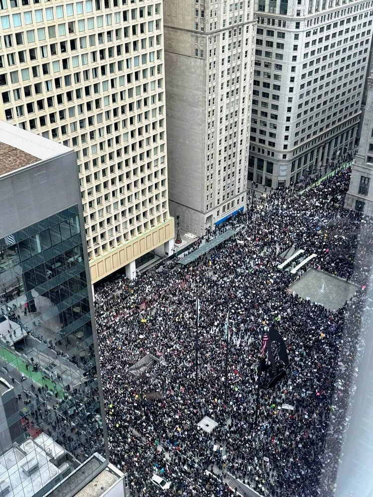 View from a window in a high rise office building looking down on Chicago's Daley Plaza and streets, all completely filled with people at rally
