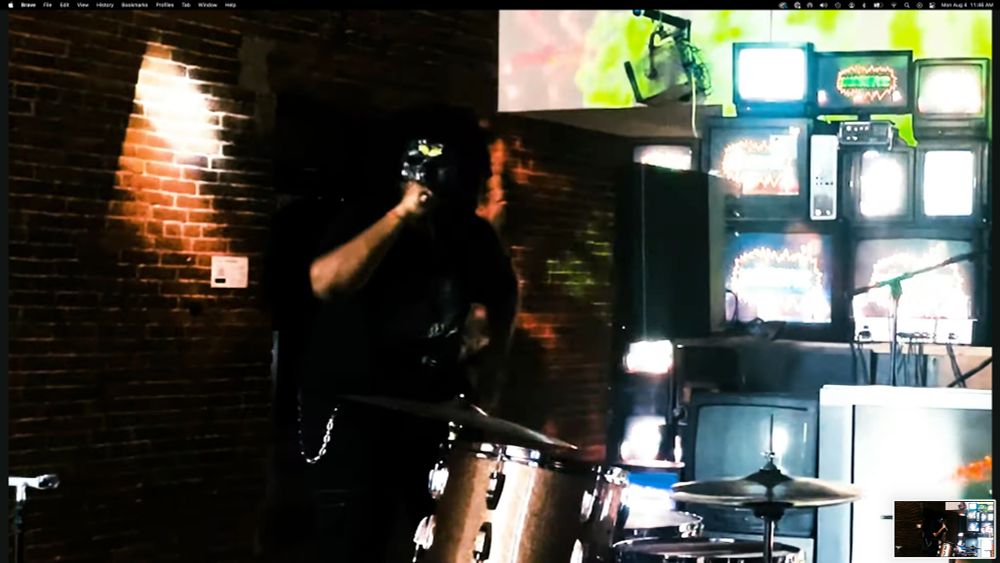 screenshot of a masked singer with mic in hand singing in front of a stack of Tube TVs