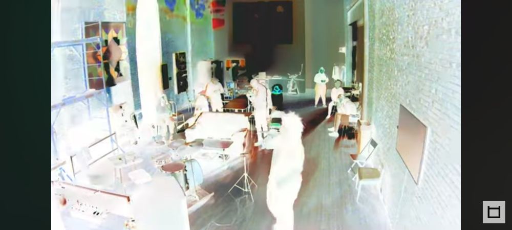 Inverted image of singer in a room with furniture, art on the walls and audience scattered throughout the space 