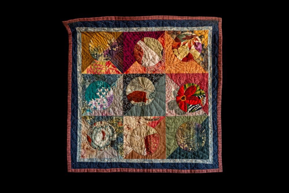 Square quilt made of 9 squares built from 4 triangles each - and each with a circle inside