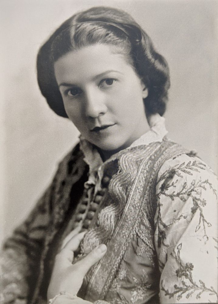 Sabiha Kasimati posing for the photographer Kristaq Sotiri in 1942. A black and white photo of a young woman wearing a nice outfit with delicate floral embroidery.