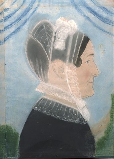 Against a clear blue sky and some vegetation, the profile of a middle-aged white woman, looking pensive. She wears a see-through white bonet adorned with a bow, and a black modest dress with white embroidery on the neck.