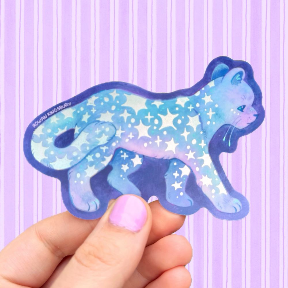 A hand holding up a sticker of a panther covered in stars