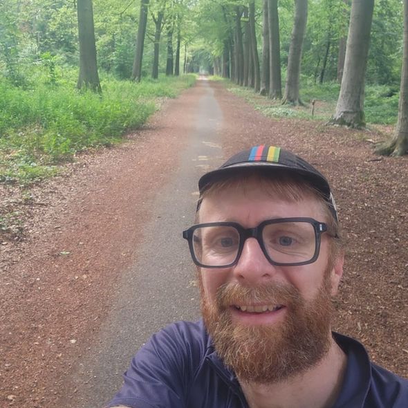 Man with glasses cycling in woods