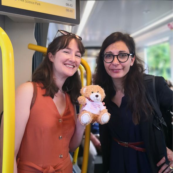 Two women with a teddy on a train
