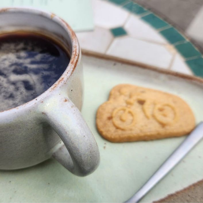 Cup of coffee and biscuit with bicycle design on it