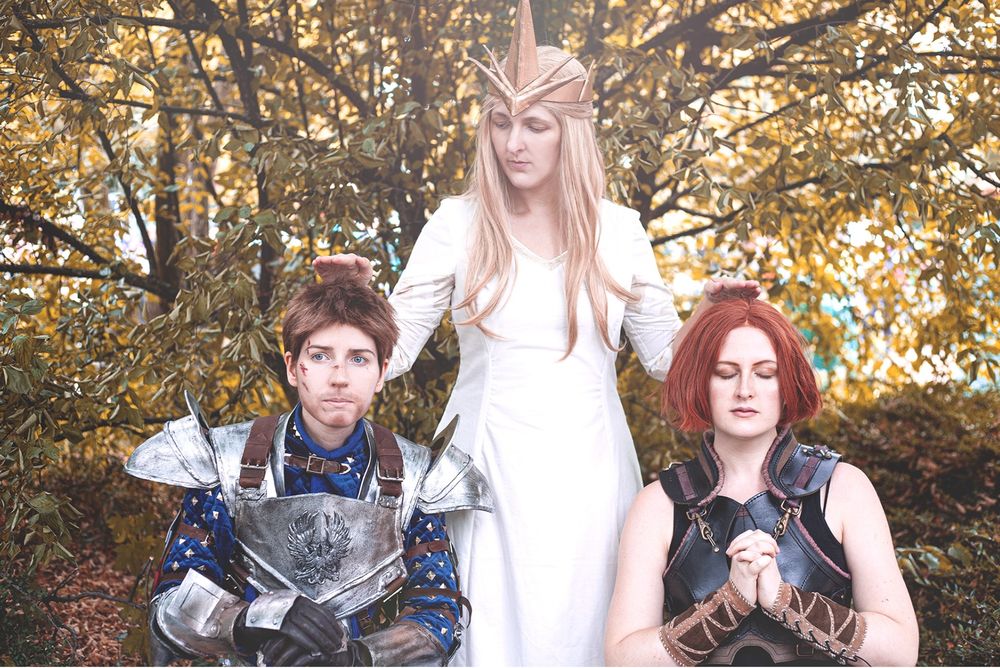 Cosplay photo of theee people as Alistair Andraste and Leliana. Alistair and Leliana are kneeling, probably in prayer and Andraste stands behind them, holding her hands over their heads as if blessing them.
Alistair seems unsure, Leliana calm.